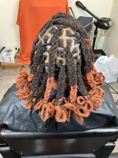 Back view of long black and orange twisted braids on a salon chair