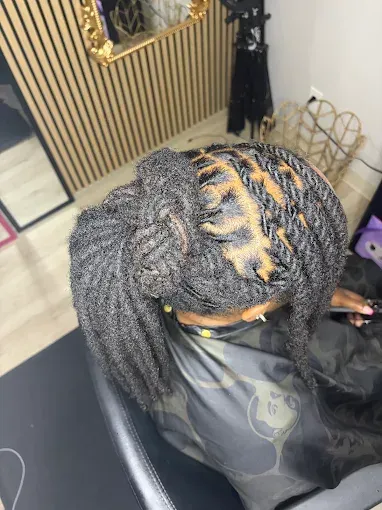 Top-down view of a braided hairstyle with gray and black extensions and gold highlights in a salon chair