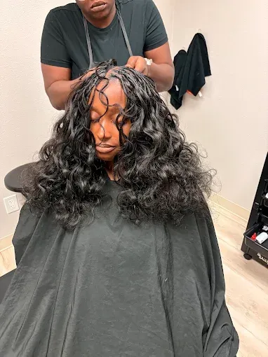 Person getting long, curly black hair styled in a salon chair.