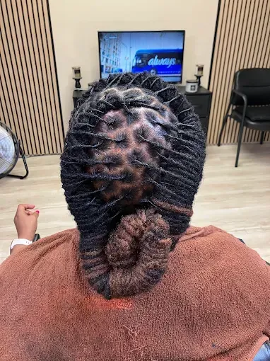 Back view of a person with braided hair watching TV in a waiting room