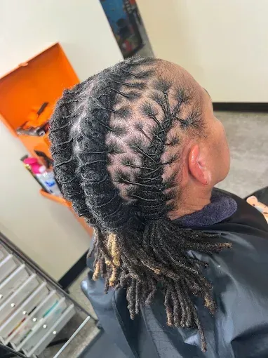 Close-up of a braided hairstyle with neat cornrows and long braids in a salon chair.