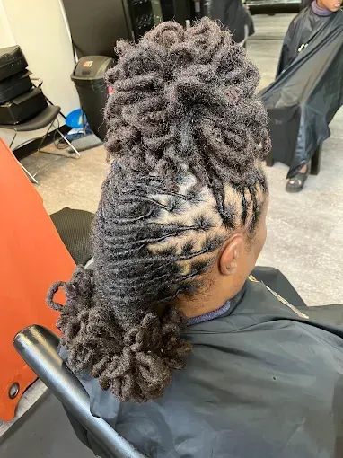Braided hairstyle with twists and a curly bun at the back in a salon chair
