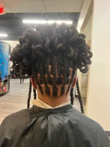 Person with large curly hairstyle and braided sections, seen from behind indoors.