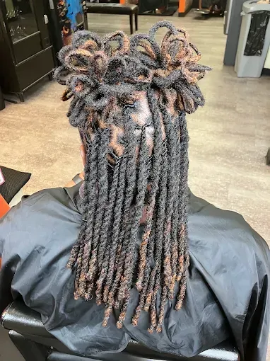 Back view of long twisted braids styled in loops, with brown and black highlights, in a salon chair