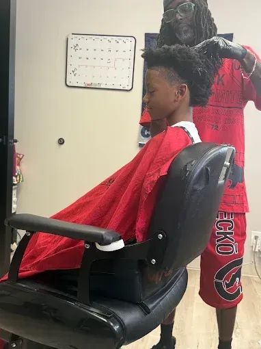 Hair styling in progress: client under red cape with stylist working in a salon chair