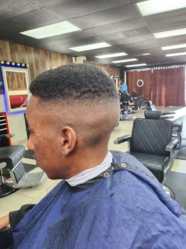 Barbershop client with a short fade haircut, seen in profile under bright ceiling lights
