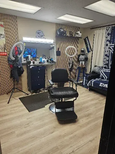 Clinic room with an exam chair, ring lights, desk, cabinets, and blue privacy curtains.