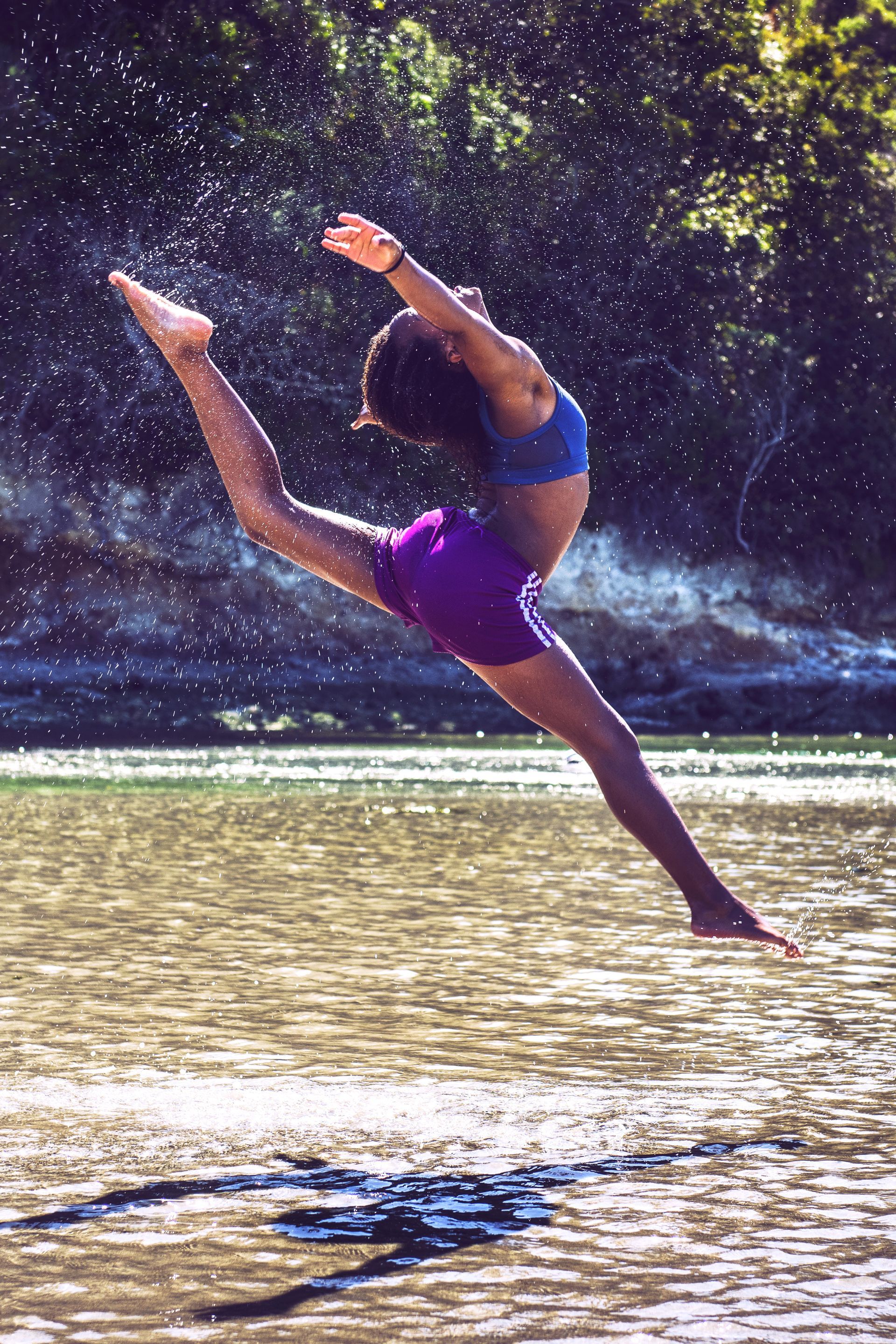 Jeune femme qui saute en grand ecart au desus de l'eau