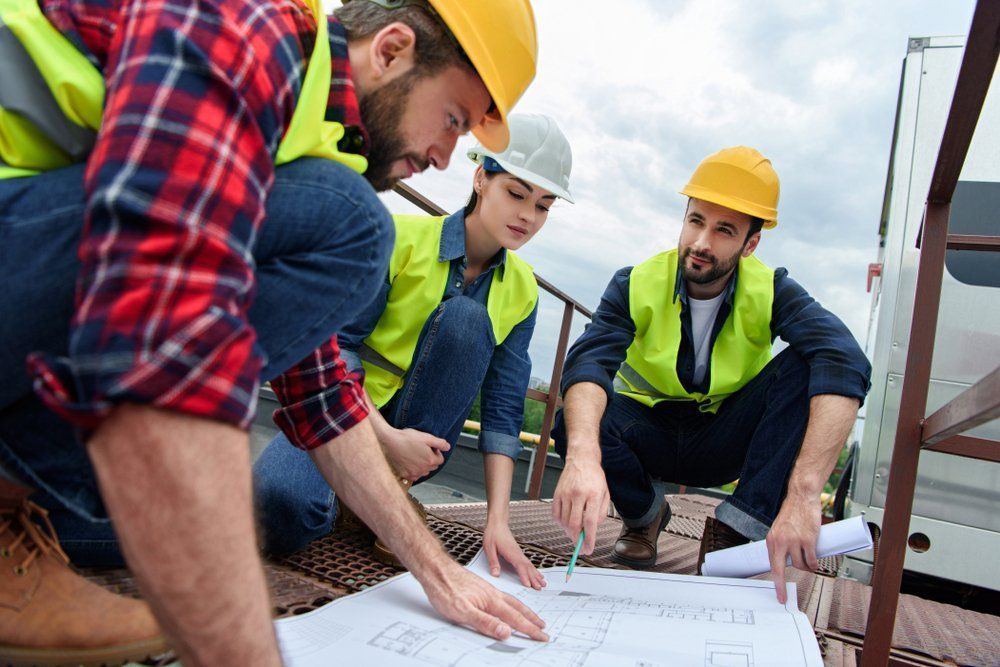 Construction Workers In Safety Gear Review Blueprints Outdoors — Wendy's Safety Services in Alice Springs, NT