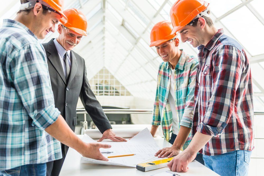 Construction Workers And A Man In A Suit Reviewing Blueprints — Wendy's Safety Services in Moulden, NT