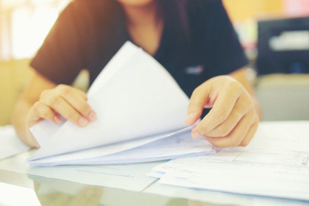 Person In Black Shirt, Hands Flipping Through A Stack Of White Papers On A Desk — Wendy's Safety Services in Moulden, NT
