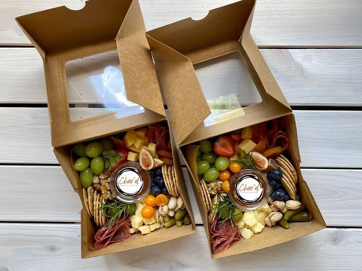 Two cardboard boxes filled with fruits and nuts on a wooden table.