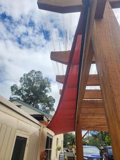A Wooden Pergola with A Red Shade Attached to It — New England Shade Sails in Tamworth, NSW