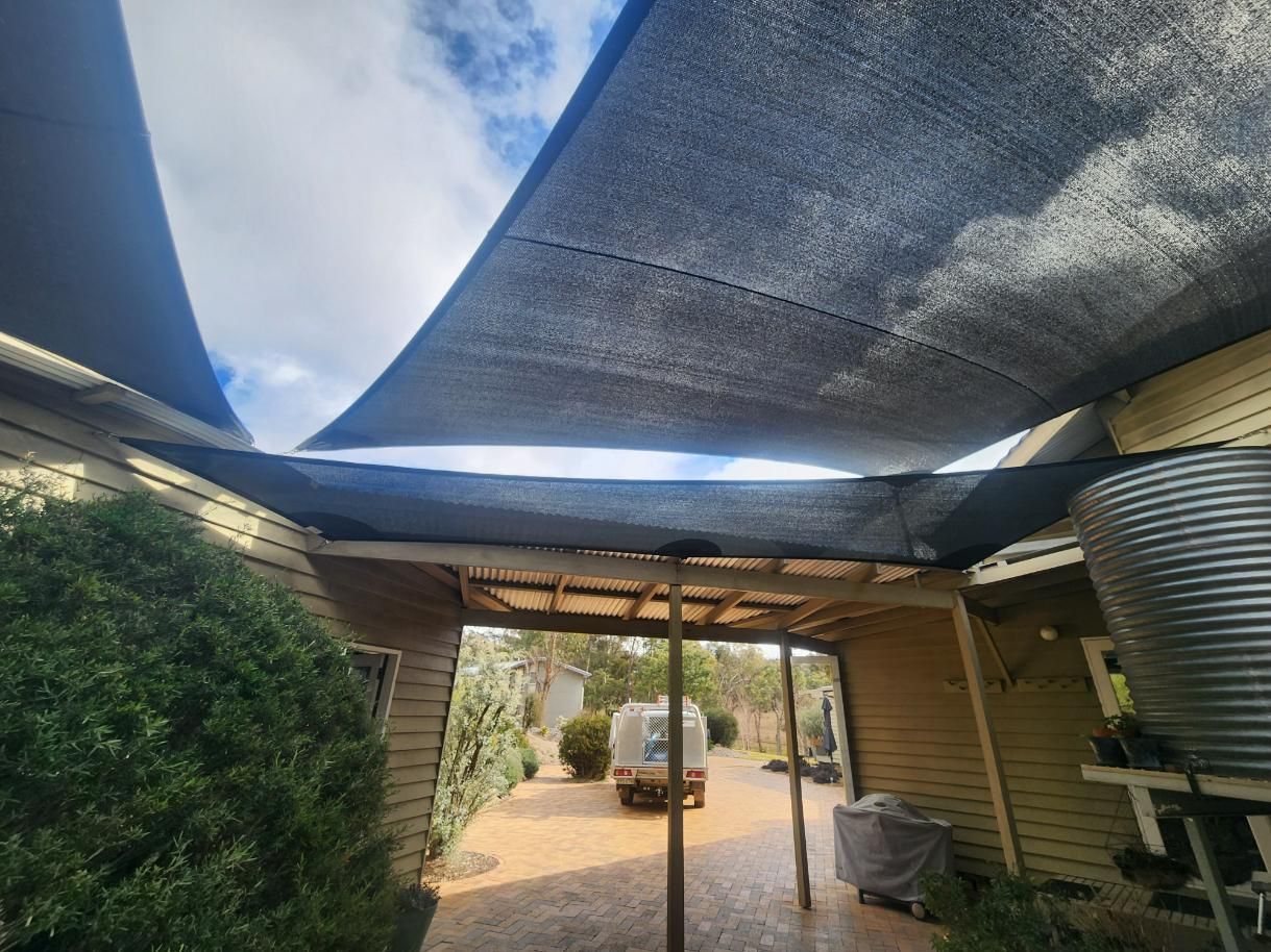 A Large Black Shade Sail Is Covering a Patio Area in Front of A House — New England Shade Sails in Tamworth, NSW