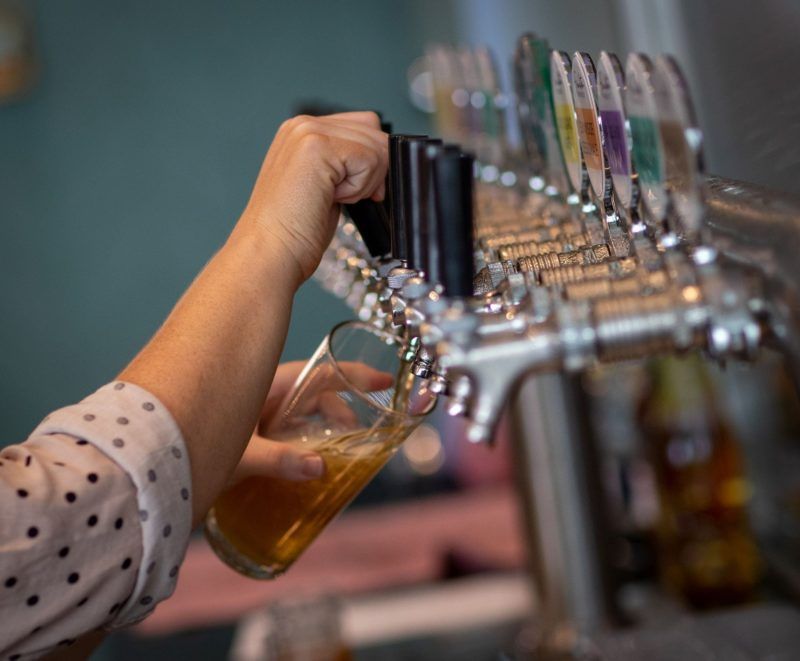 person pouring beer at bar from beer tap