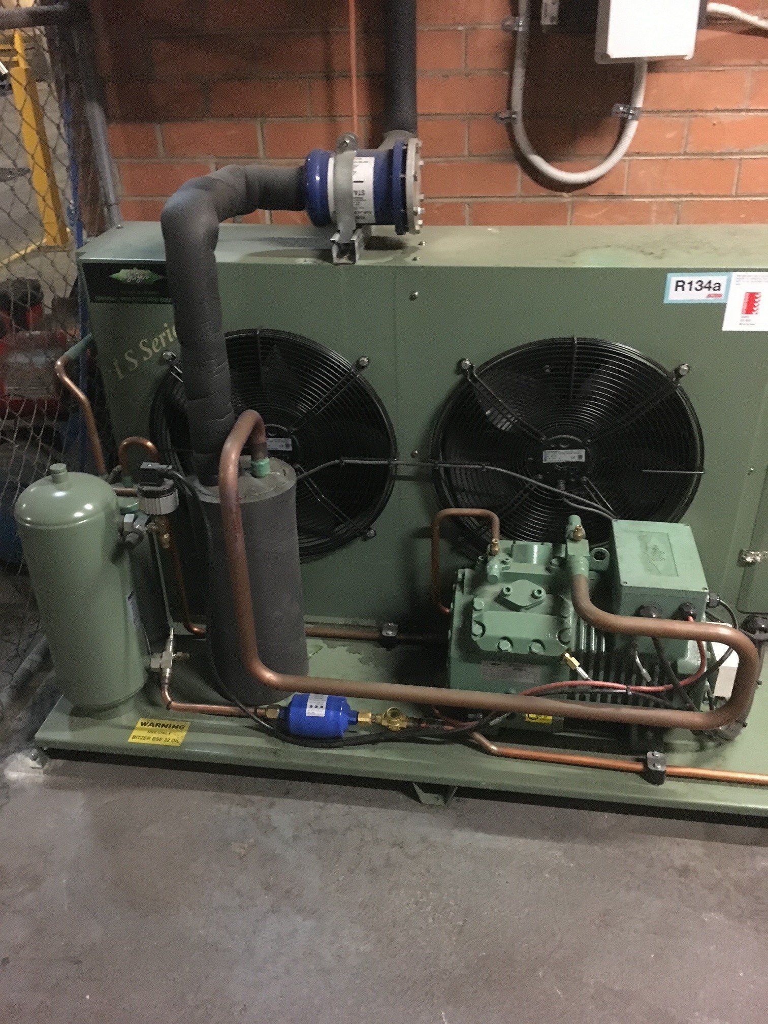 a green air conditioner is sitting in a room next to a brick wall .