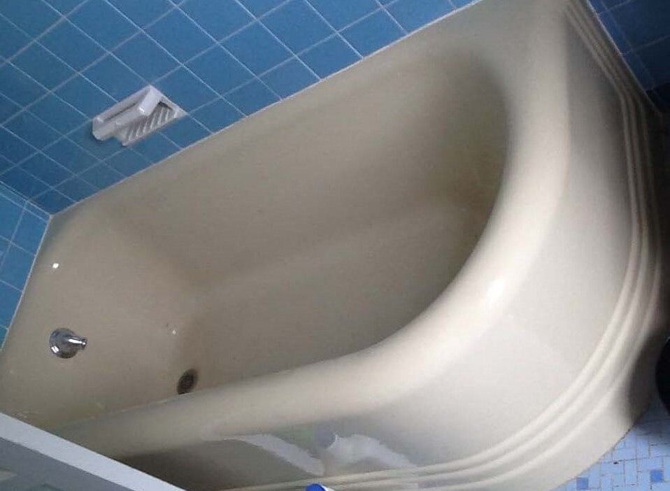A bathtub in a bathroom with blue tiles.