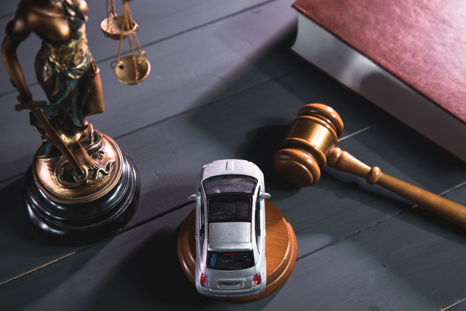 Statue of justice, gavel, and toy car on a desk, suggesting a legal dispute over a vehicle.