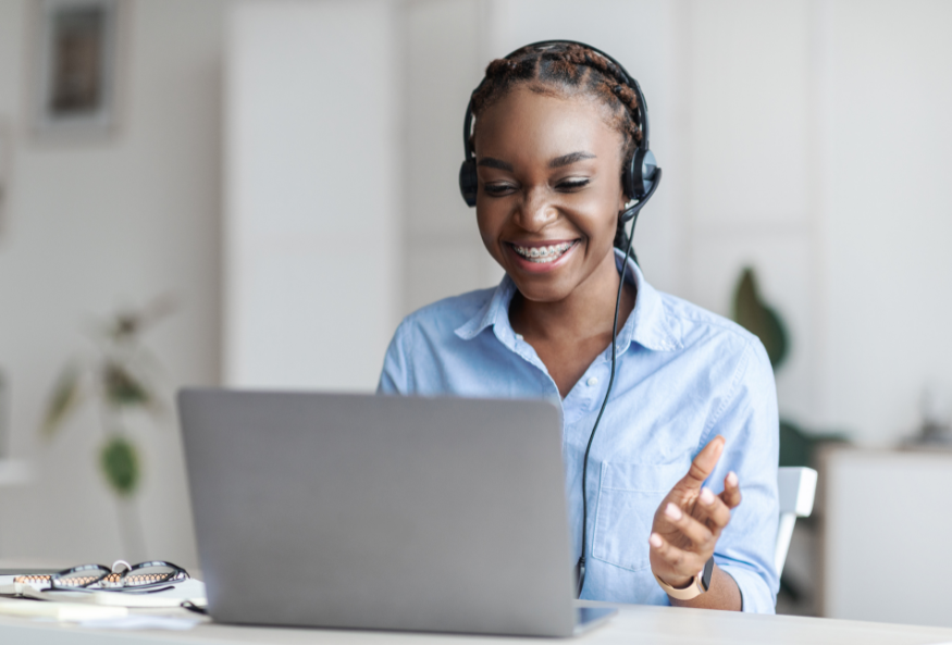 A woman wearing headphones is sitting in front of a laptop computer.