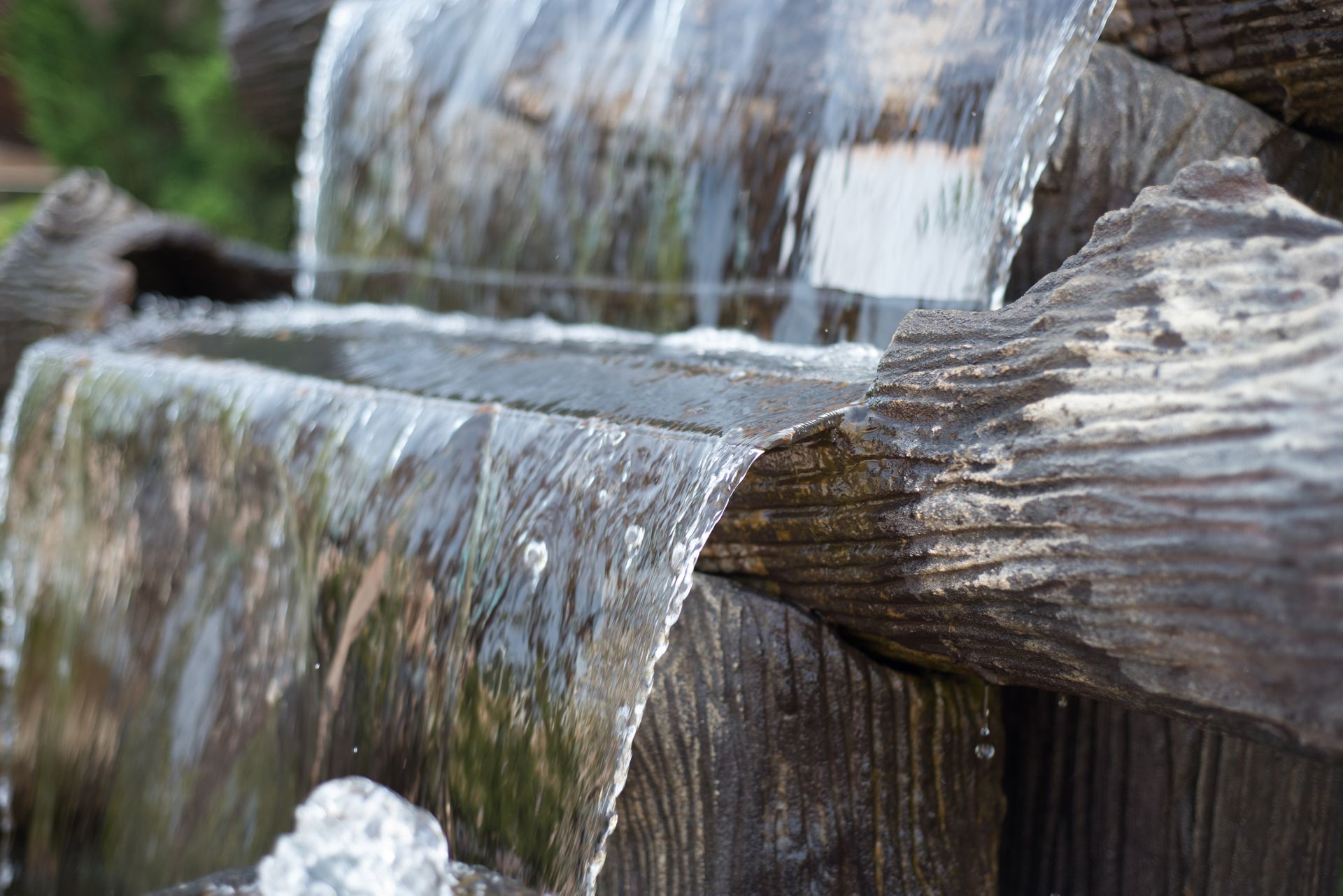 Close-up of water cascading over stacked wooden beams in a small waterfall or fountain