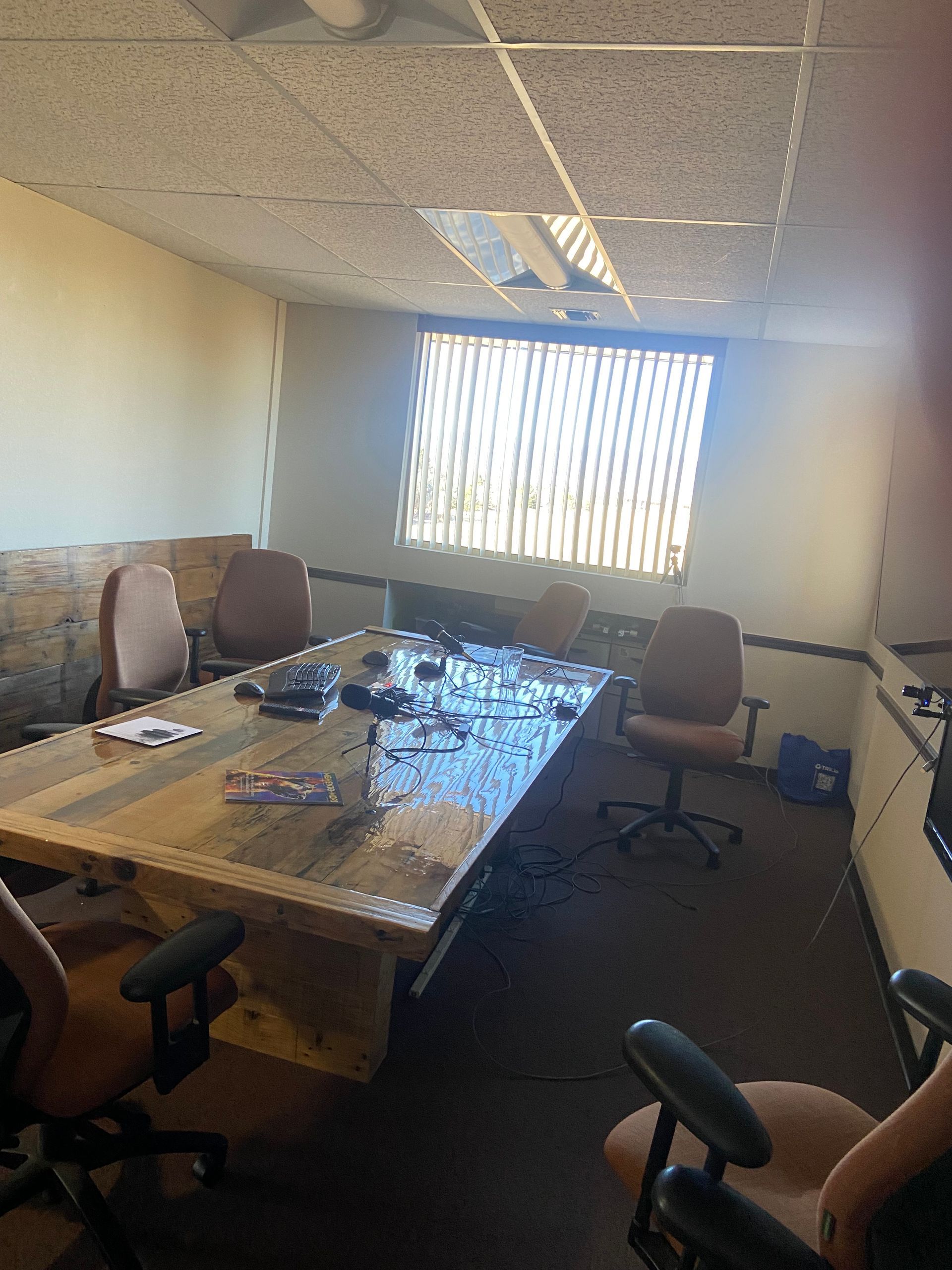 Conference room with a large table, office chairs, and a bright window with blinds.