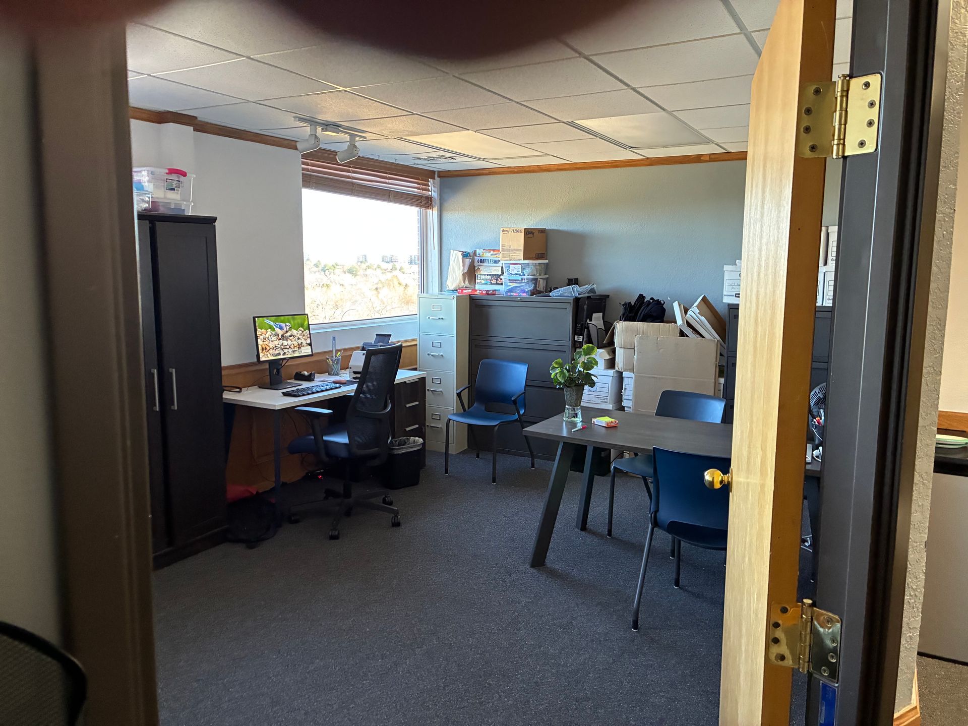 Office cubicle with desks, chairs, and computer monitors near a window.