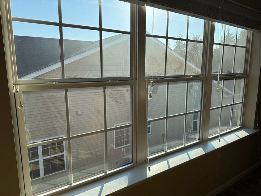 A bright, multi-paned window looking out at the beige siding and roofline of an adjacent house.