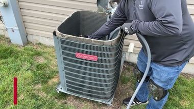 Person connecting pipes to an air conditioning unit.
