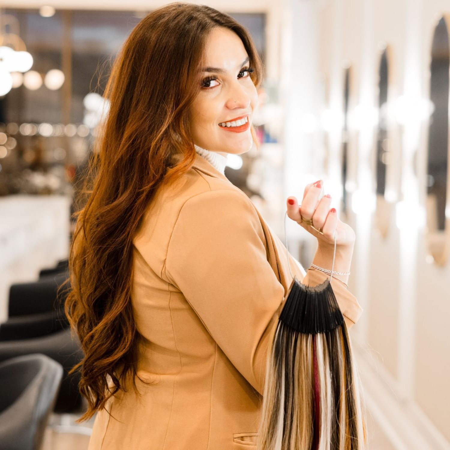 Woman holding hair extension swatches, smiling in a salon.
