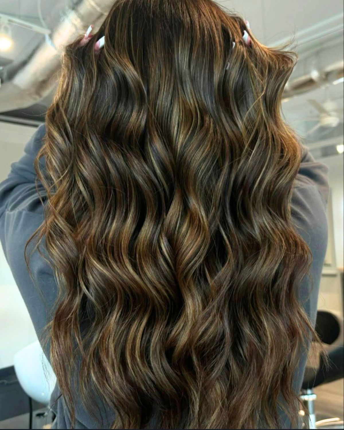 Long, wavy brown hair with blonde highlights.