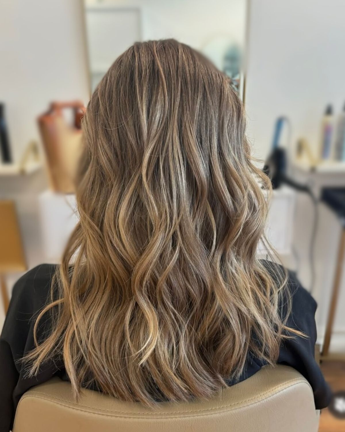 Woman's wavy, highlighted hair at a salon. Golden and brown tones with gentle waves.