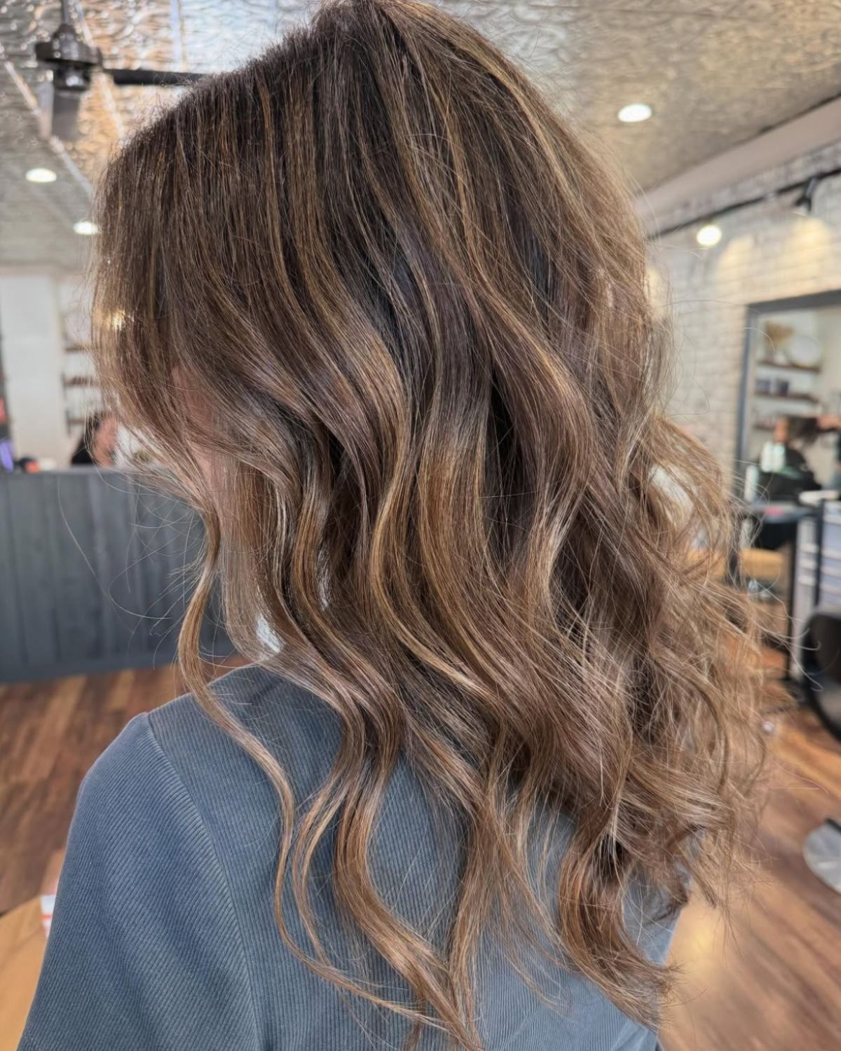 Woman with wavy brown hair with blonde highlights.