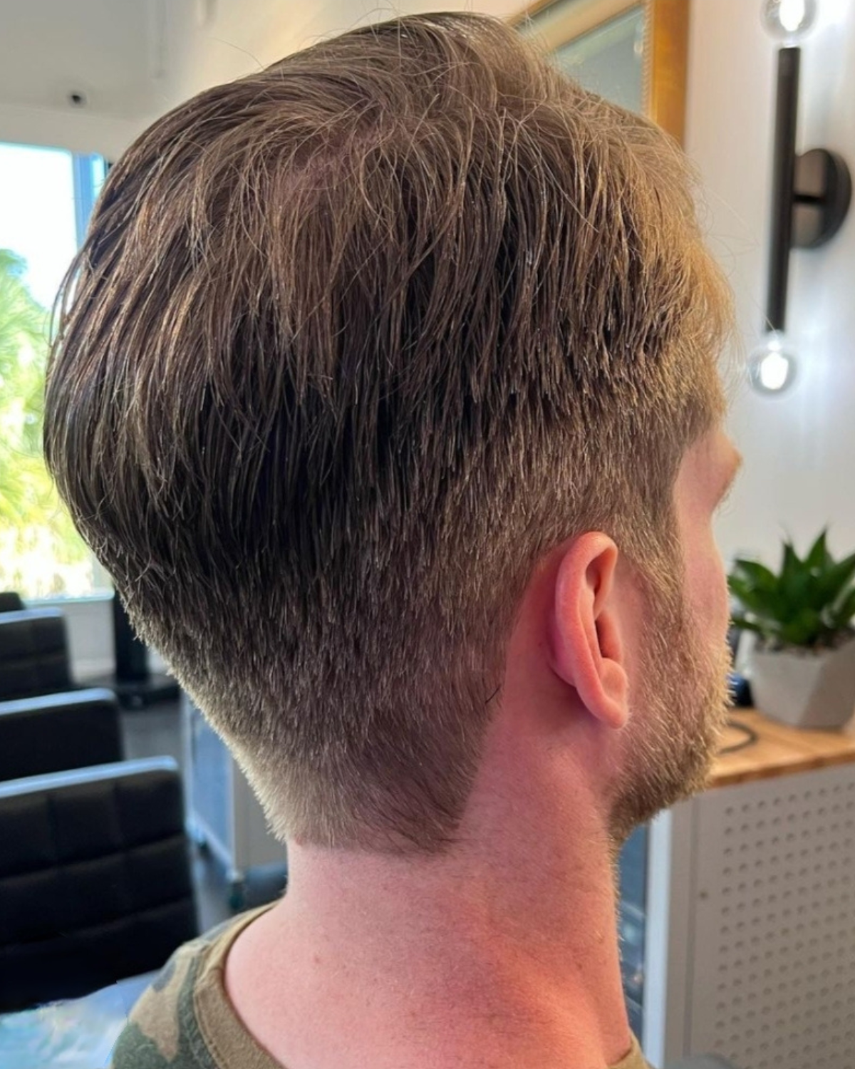 Man with a short haircut, viewed from behind and to the side. The hair is light brown, fading to the nape.