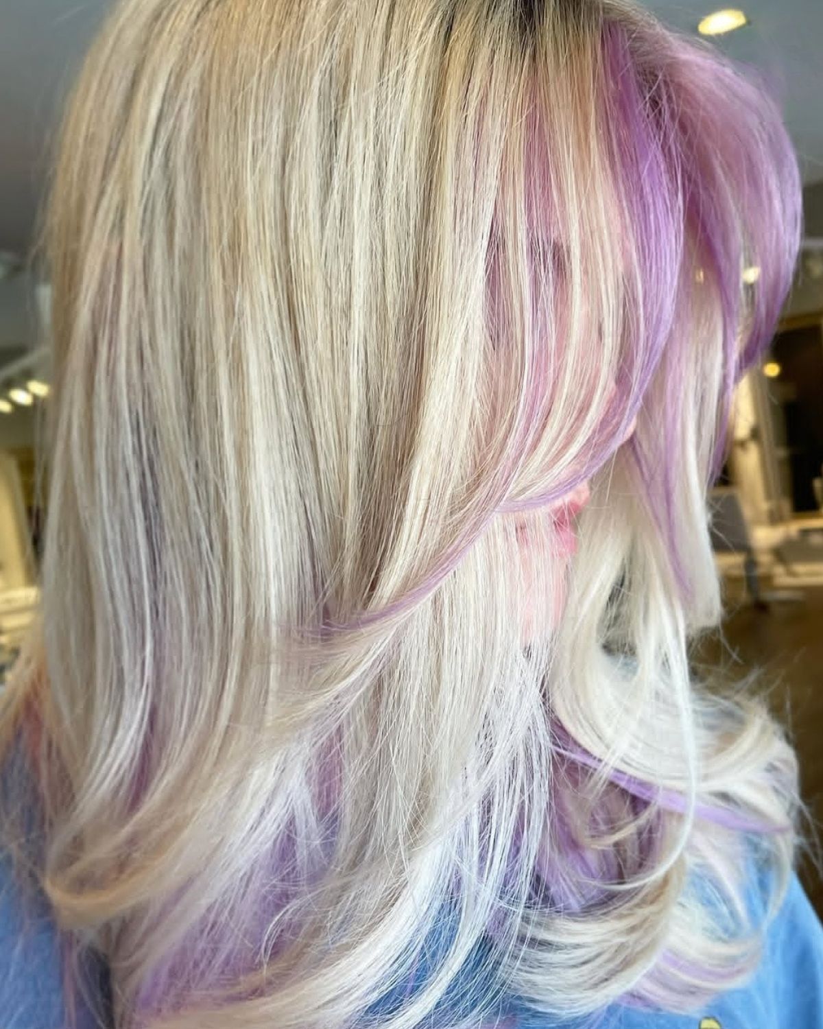Blonde hair with strands of purple, layered style. Indoors, natural light.