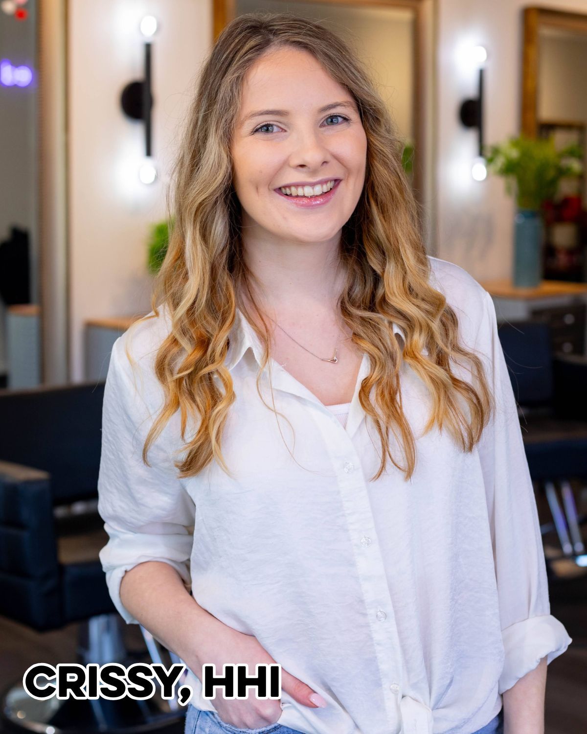 Woman smiling in a white shirt, with wavy blonde hair, inside a salon. Text