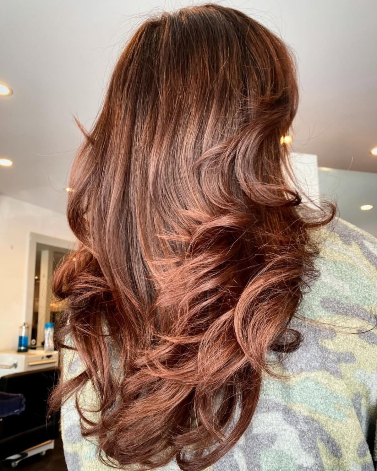 Long, wavy reddish-brown hair, styled at a salon.