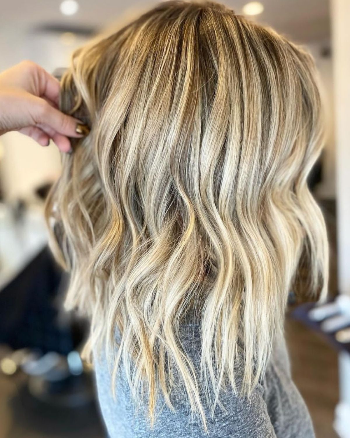 Blonde wavy hair with highlights. A hand holding up the hair.