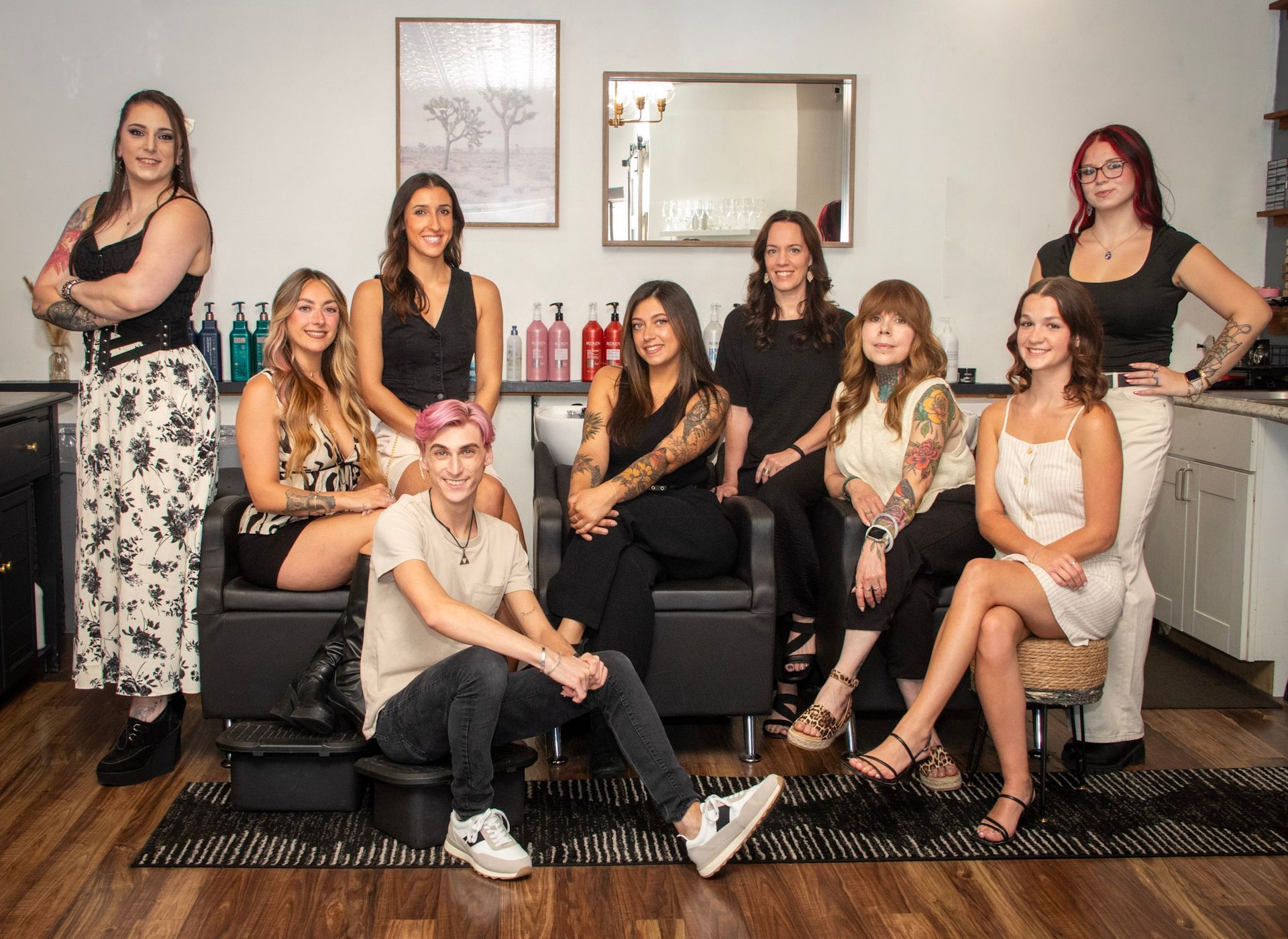 Salon team posing indoors, nine people: diverse, smiling.