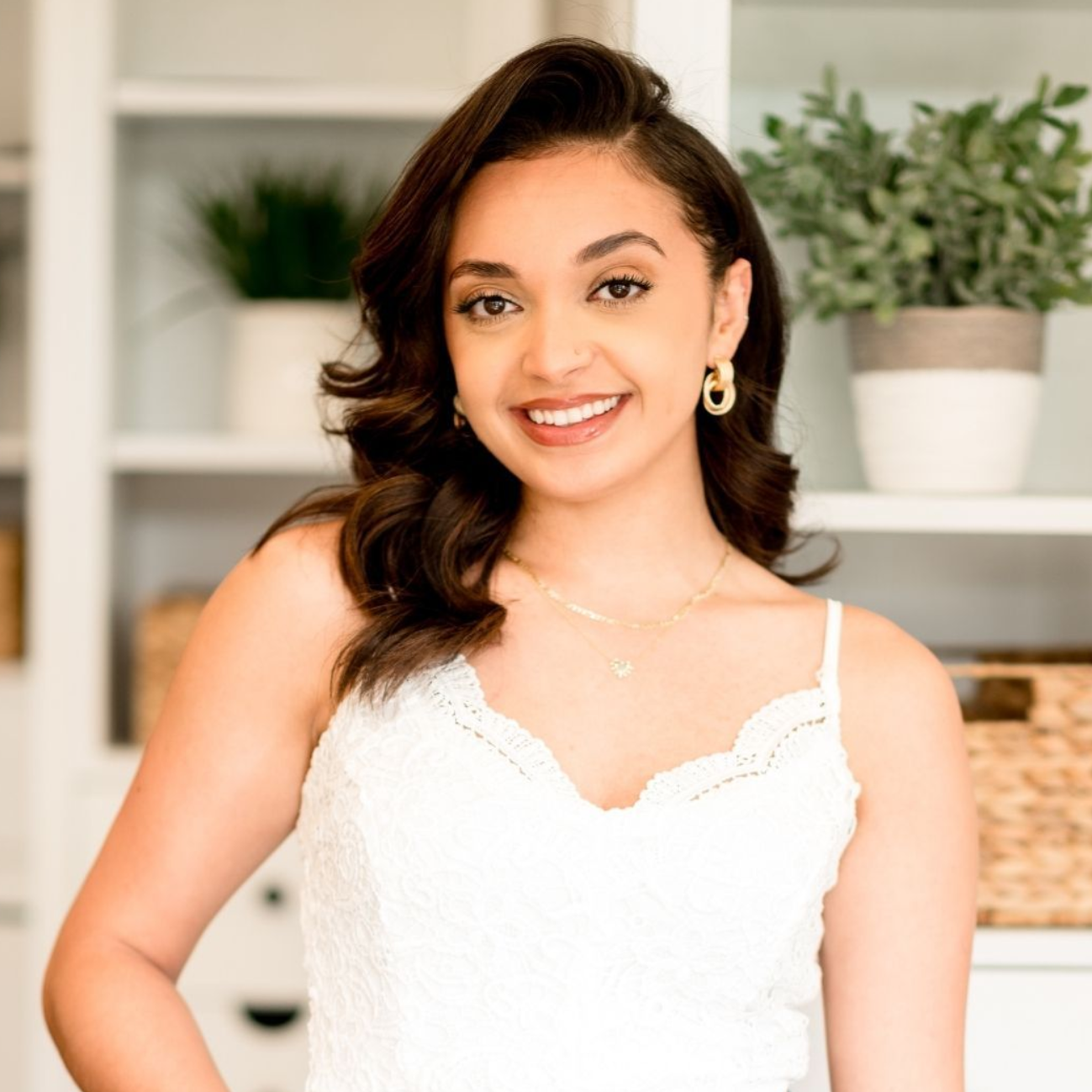 Woman in white top smiles, looking towards the camera.