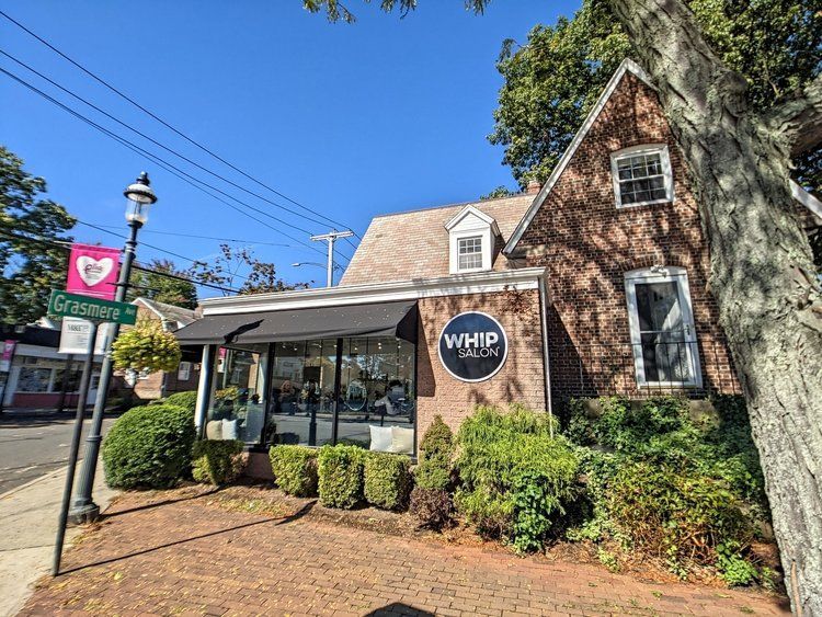 A brick building with a sign that says whip salon on it.