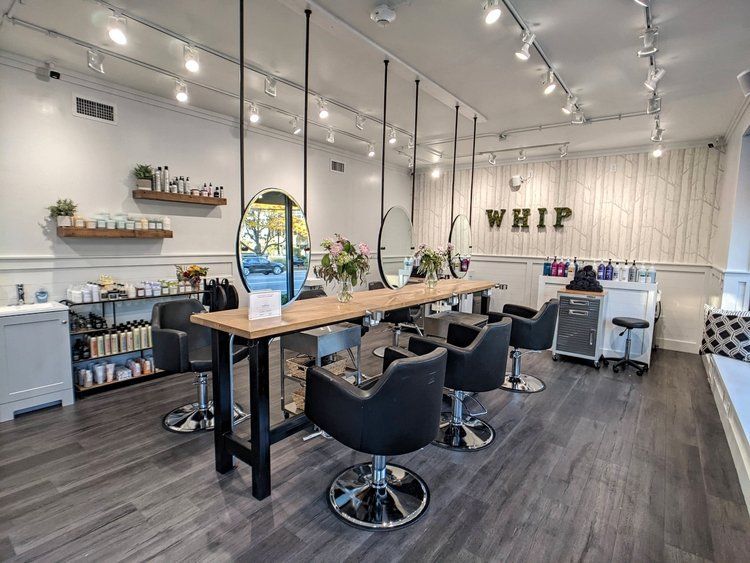 A hair salon with lots of chairs and a table.
