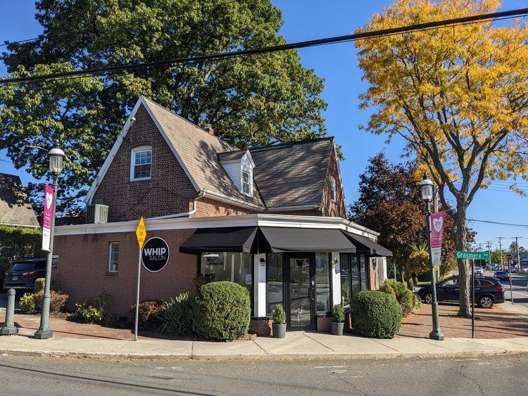 A brick building with a black awning is on the corner of a street.