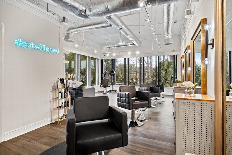 A hair salon with a lot of chairs and a mirror.