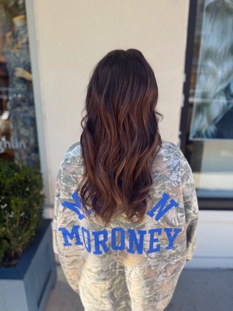 Woman with brown hair, wearing a camo jacket with