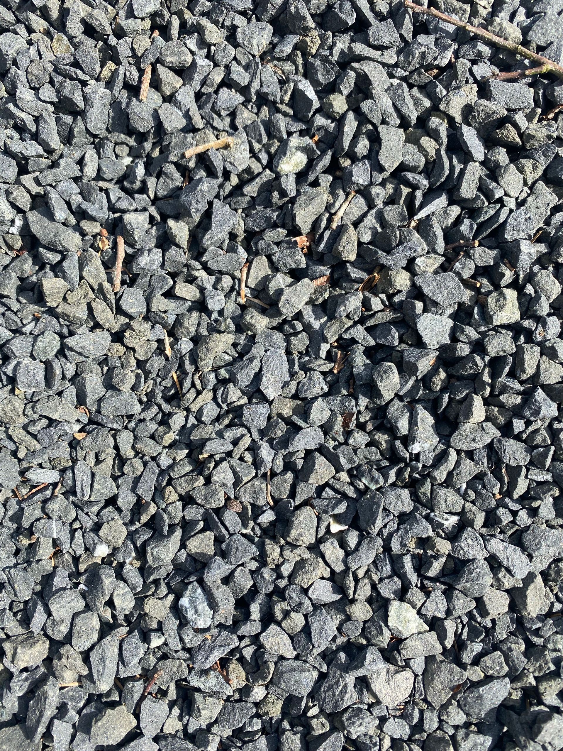 Close-up of rough gray gravel stones with scattered tan and orange pieces