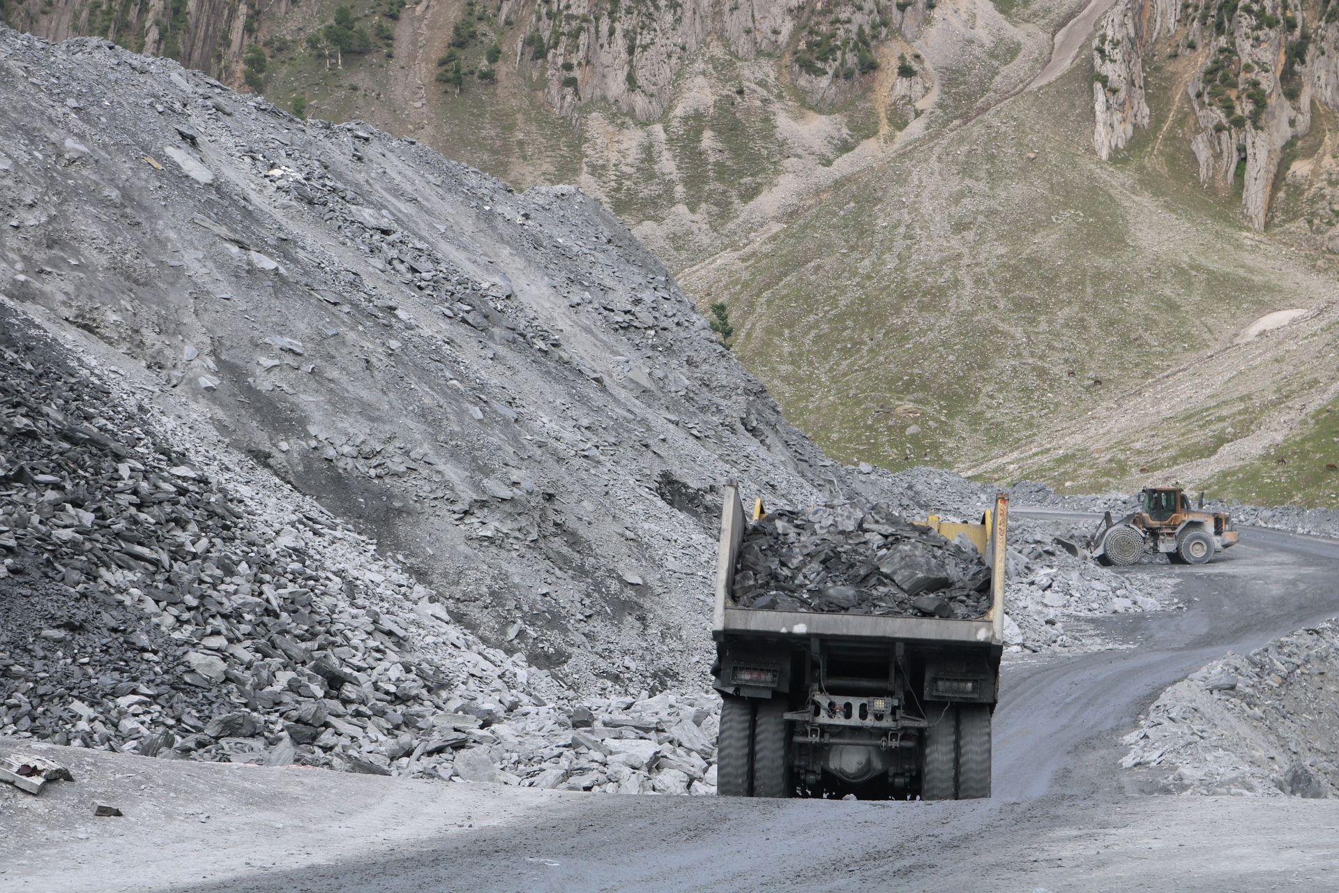 Large mining dump truck on a gravel road in a rocky quarry