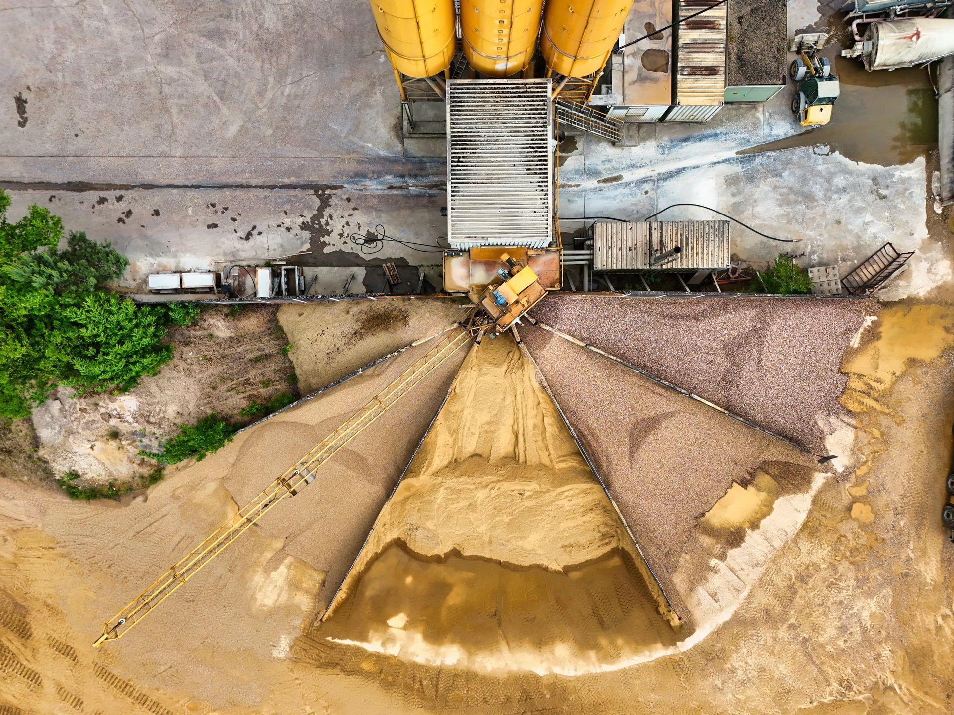 Overhead view of a concrete silo emptying tan grain into a central chute.