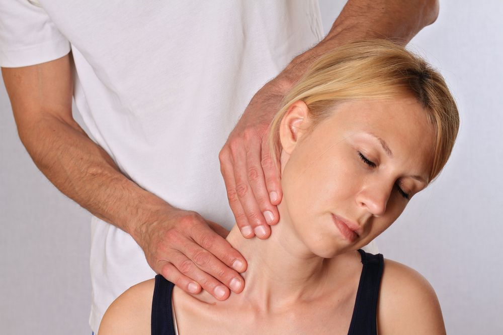 A Woman is Getting a Neck Massage From a Chiroprator — Cobargo Chiropractic in Cobargo, NSW