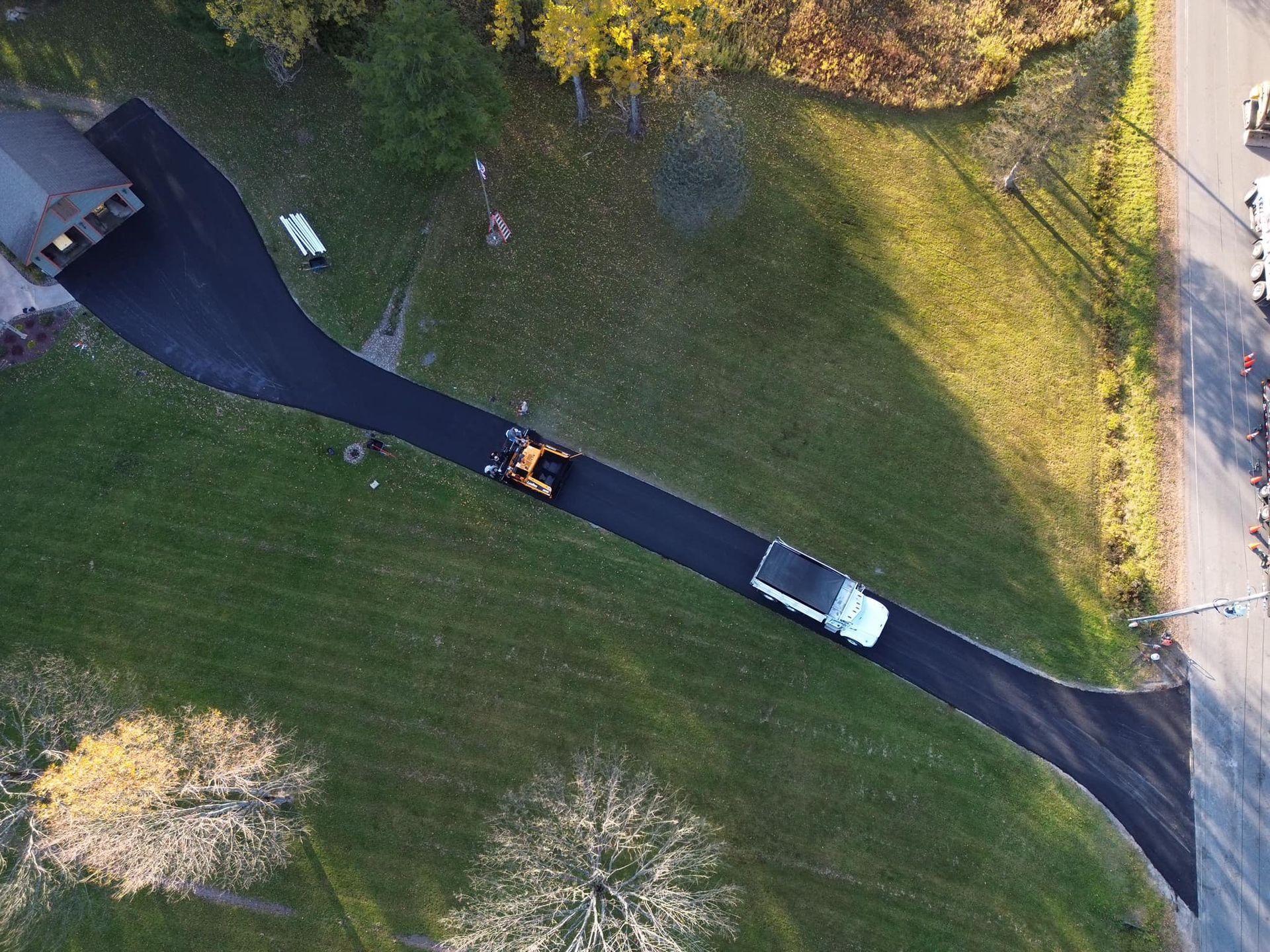 Aerial view of a driveway with two parked vehicles beside a house and a grassy yard