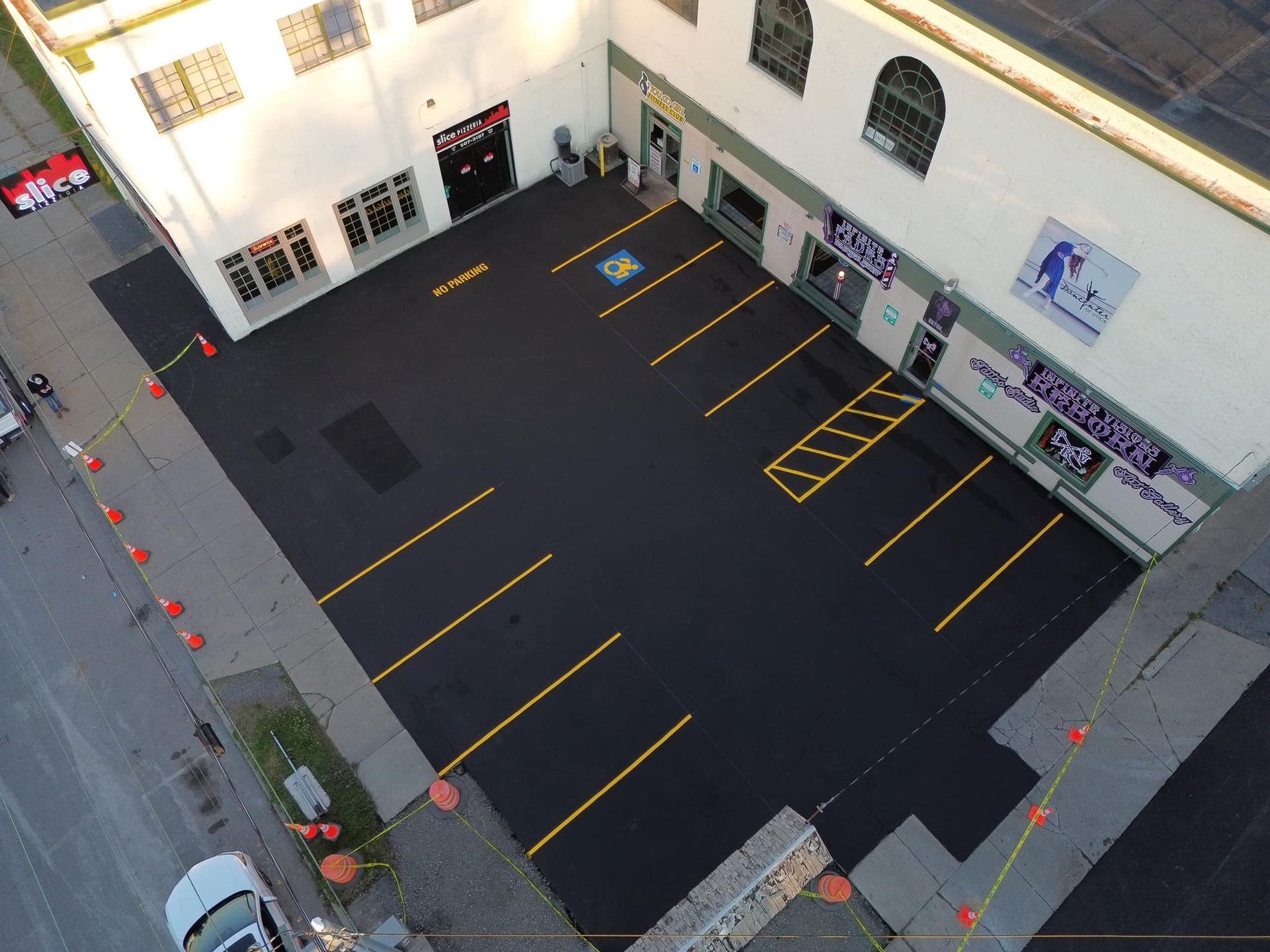 Empty blacktop parking lot with yellow lines beside a building courtyard